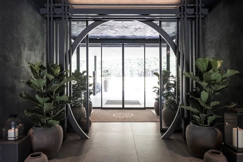 Entry foyer with octagonal steel portal frame flanked by potted plants and candlelit alcoves
