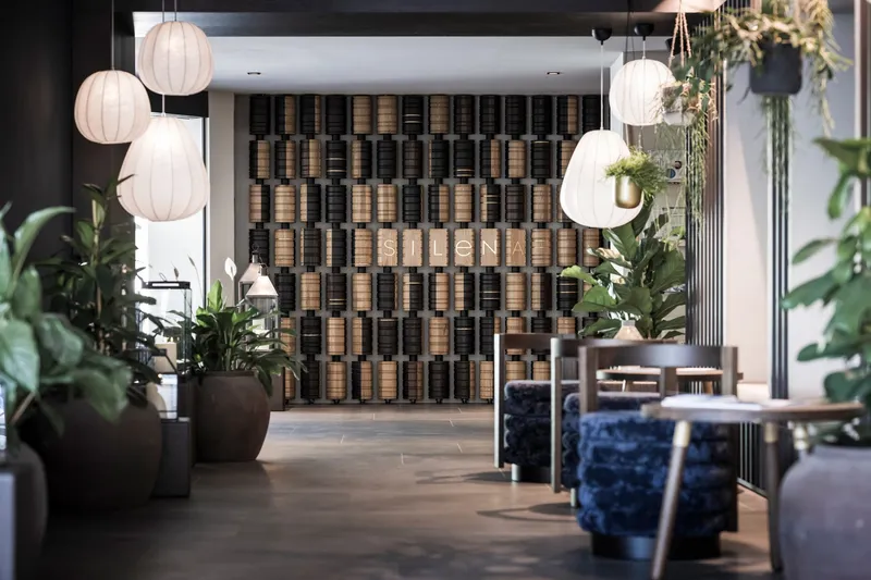 Lobby space with checkered acoustic panel wall, spherical paper lanterns and potted tropical plants