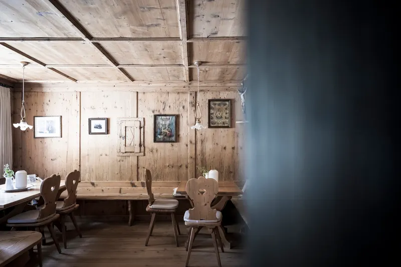 Dining alcove with weathered timber plank walls, exposed ceiling beams and traditional carved wooden chairs