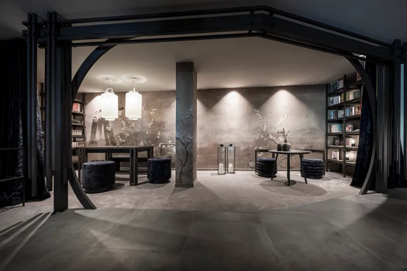 Arched steel frame opening into lounge area with illuminated textured walls and black timber screens