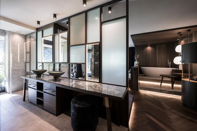 Double vanity with vessel sinks set against translucent glass partition panels framed in dark metal