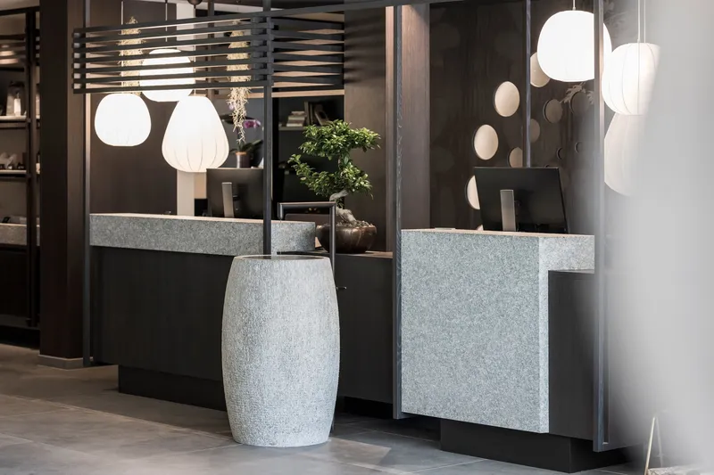 Freestanding terrazzo basin beside counters clad in matching stone with pendant lighting above