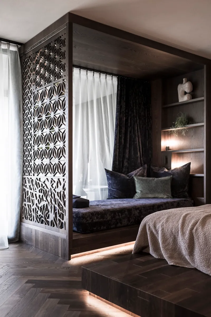 Geometric lattice screen wrapping the corner of a built-in window seat niche with shelving
