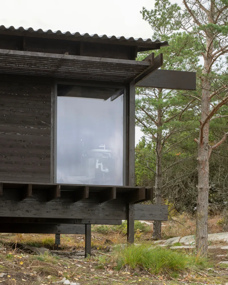Corner window detail with blackened timber cladding and deep overhang supported by exposed timber posts