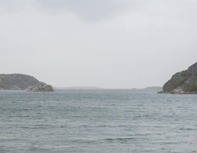 View across grey water toward rocky islands under overcast sky