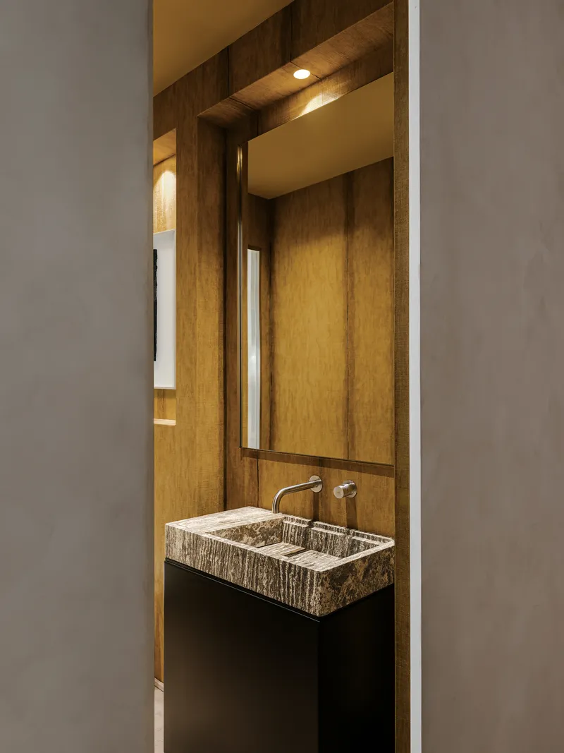Powder room vanity with striated stone basin and wall-mounted faucet framed by grey walls