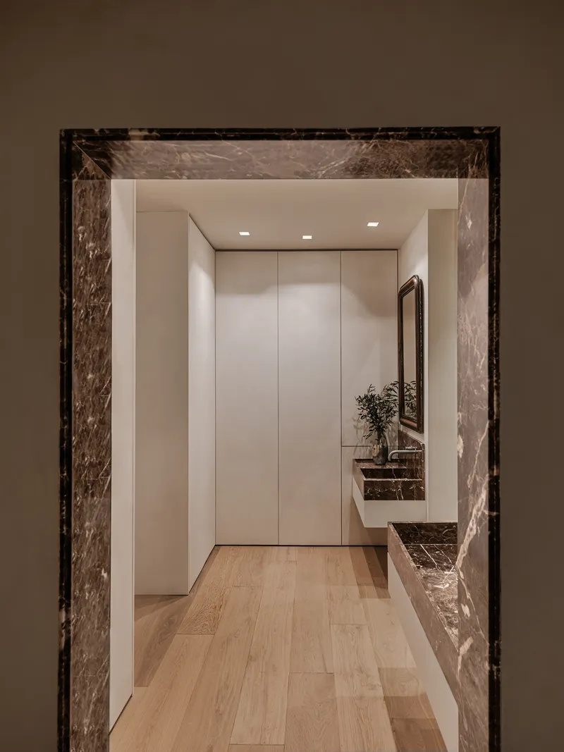 Entrance hall with veined marble door surround, flush cabinetry, and wood flooring