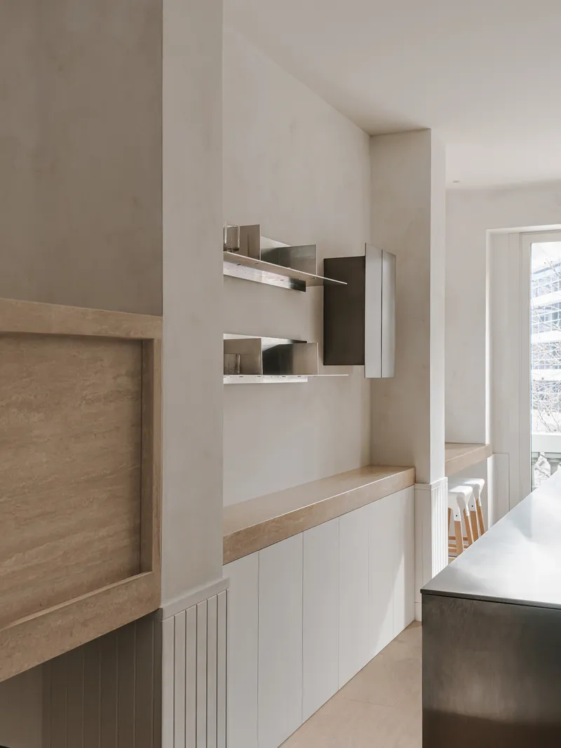 White cabinetry with timber countertop and floating shelves displaying architectural model fragments