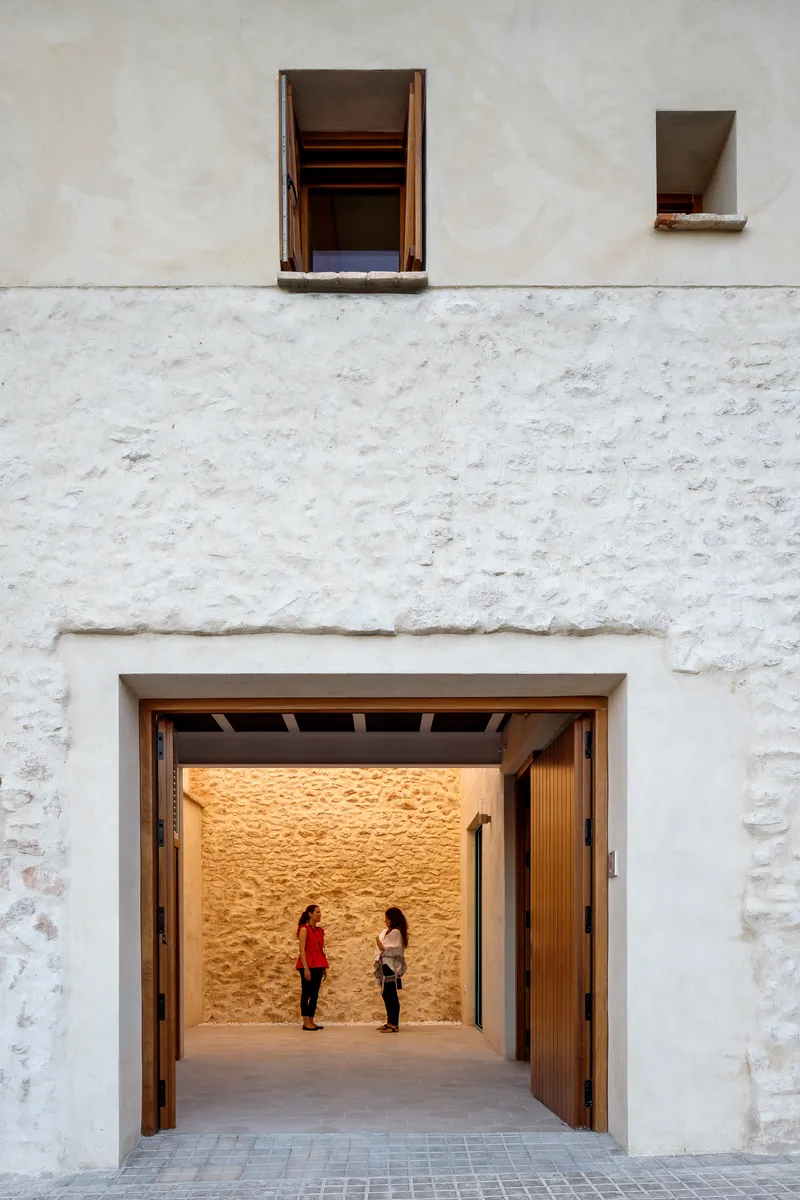 Large timber-framed entrance opening with exposed beam ceiling and two figures inside the stone-walled interior