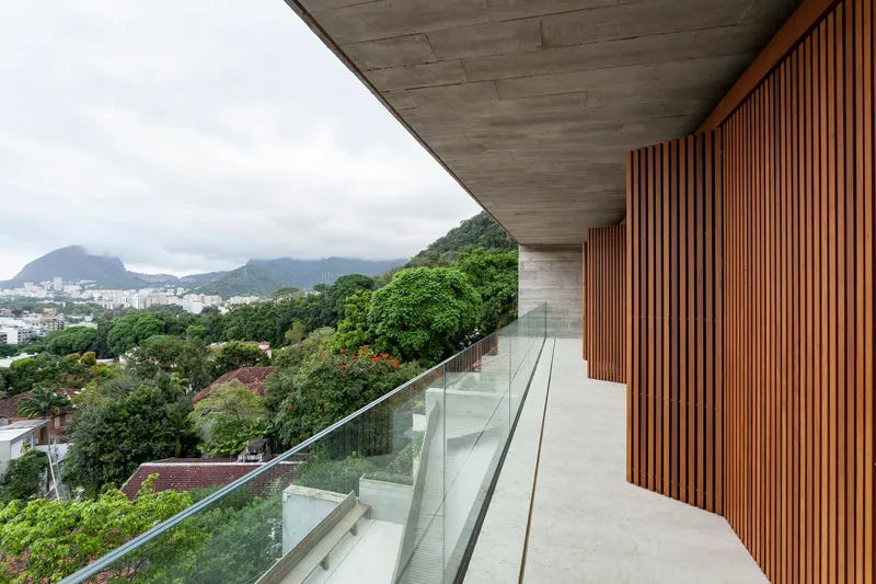 Covered walkway with timber slat wall and glass railing above dense vegetation