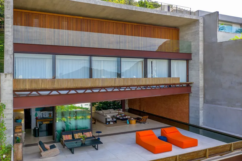 Open terrace with orange loungers beneath cantilevered floors and timber lattice railings