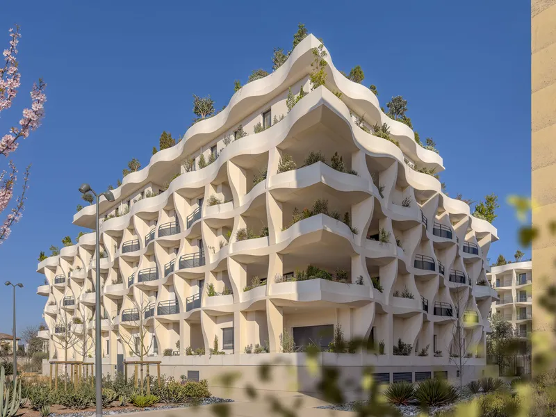 Full view of the sculptural facade with terraced balconies and rooftop vegetation