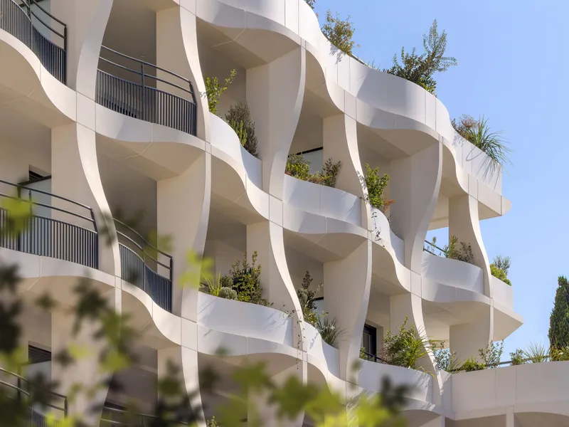 Close view of the sculpted white balconies with greenery emerging from planters