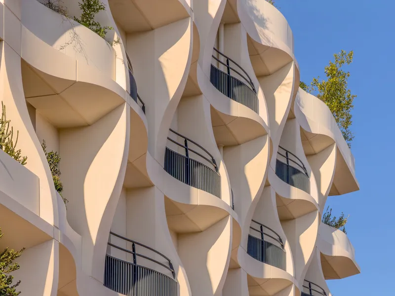 Close-up of the sinuous balcony edges and metal railings with scattered greenery between floors