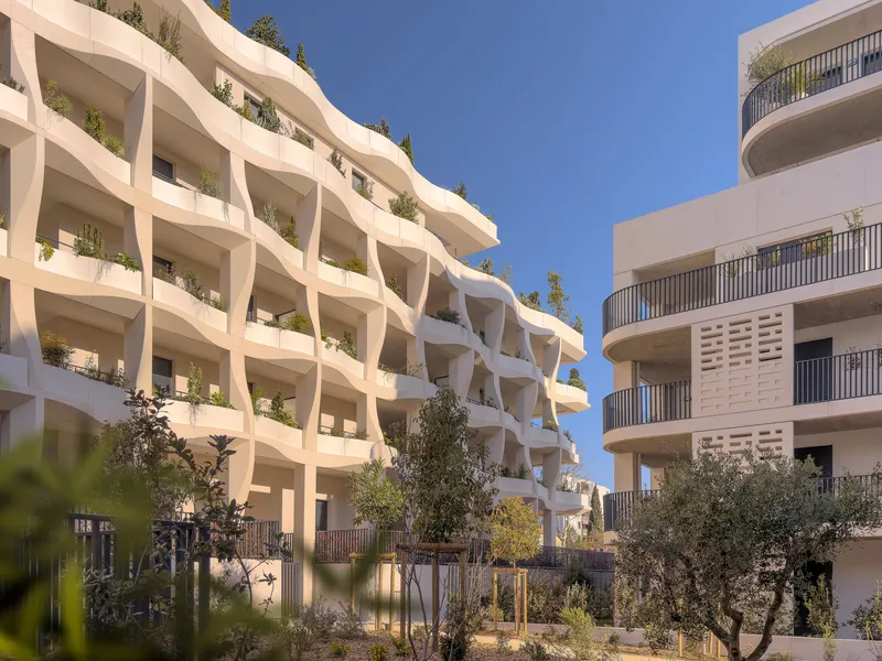 Diagonal view of the facade with landscaped ground level courtyard and neighboring residential block