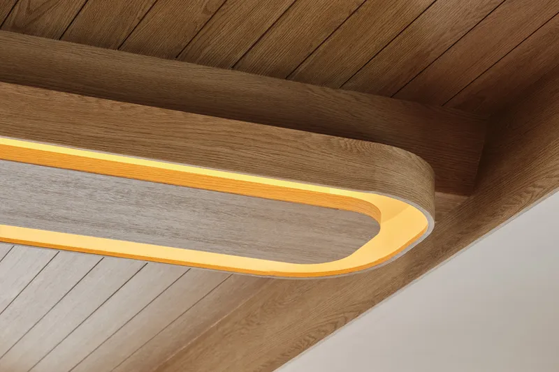 Close-up of the rounded timber ceiling element with integrated lighting against wood-planked ceiling