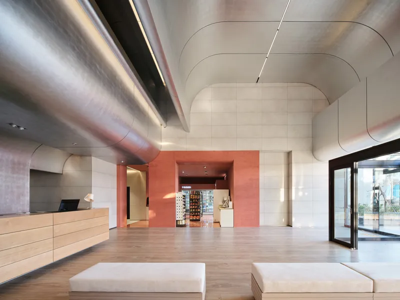 Lobby view toward coral-colored retail alcove with exposed metal ducts spanning the ceiling