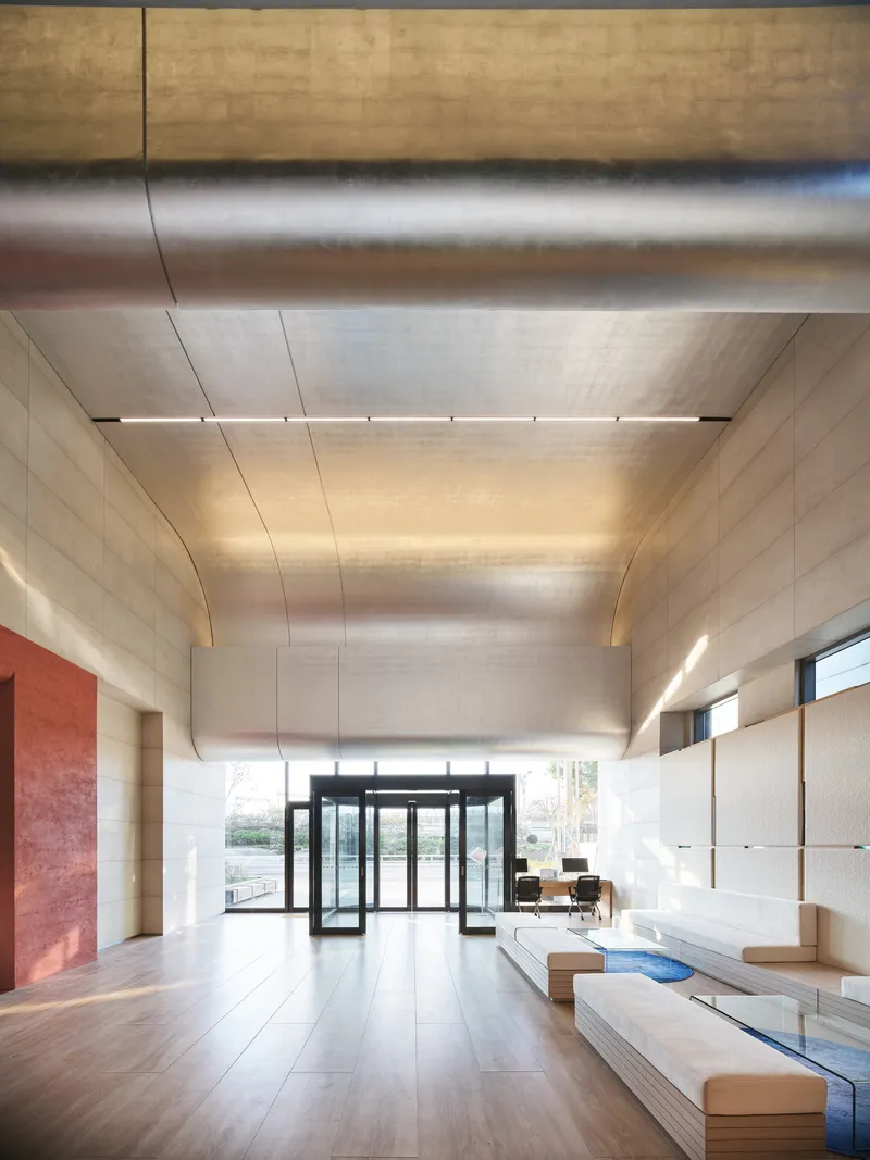 Lobby interior with exposed metal ductwork, glass entrance vestibule, and built-in seating along one wall