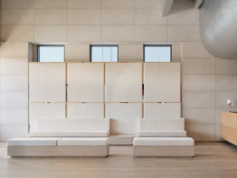 Interior wall with pale wood cabinetry and four translucent sliding panels above a low platform seating arrangement