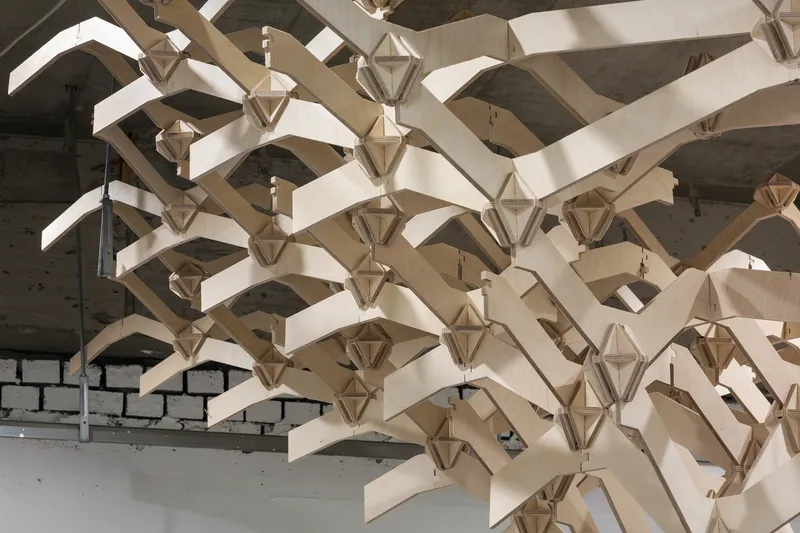 Underside view of the laminated timber canopy with polyhedral node connections and curved branch elements