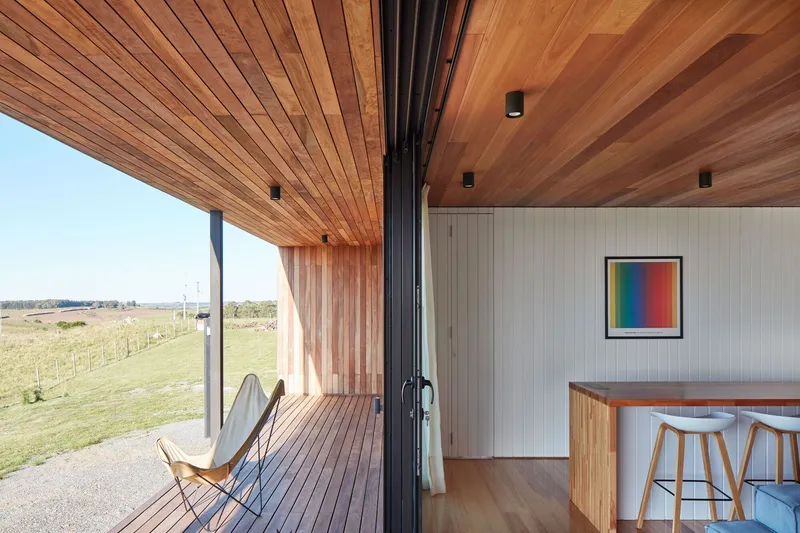 Covered timber deck with folding glass doors connecting interior to landscape beyond