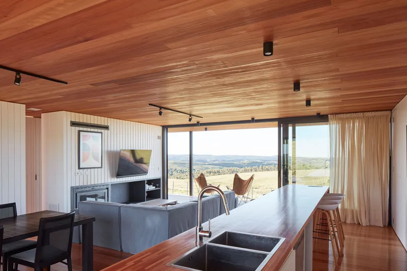 Open plan kitchen and living area with timber flooring and ceiling overlooking farmland
