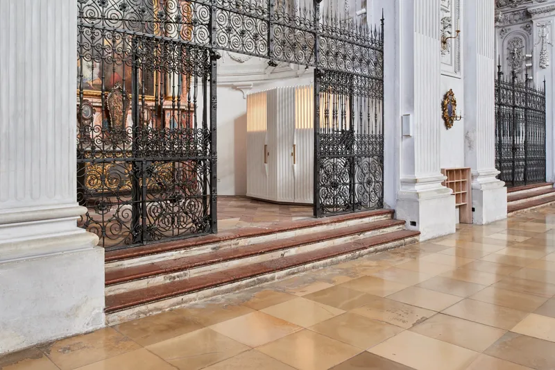 Low marble steps leading up to the wrought iron enclosure with vertical ribbed timber volumes beyond