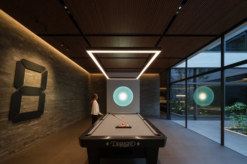 Billiards room with circular backlit artwork on white wall and a figure in motion beside the table