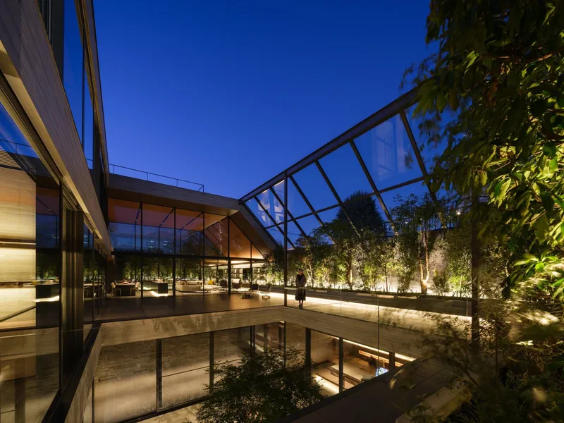 Interior courtyard with glazed roof and planted bamboo grove illuminated at dusk