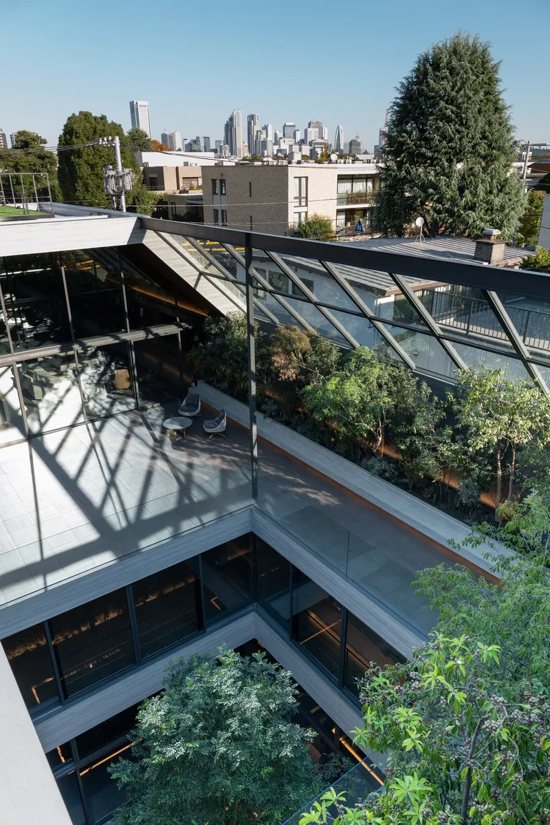 Rooftop terrace with angled glazed canopy, planted beds and steel structure overlooking distant skyline
