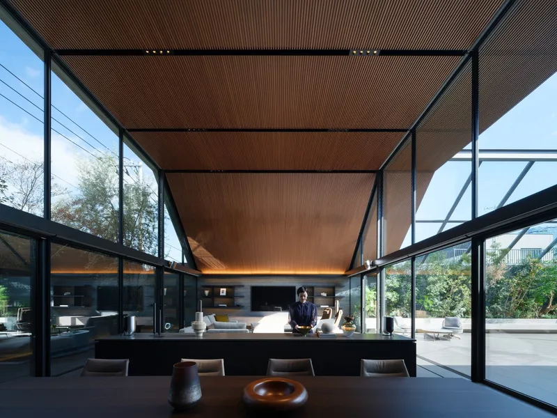 Interior dining area beneath a linear timber ceiling framed by steel structure and glass walls