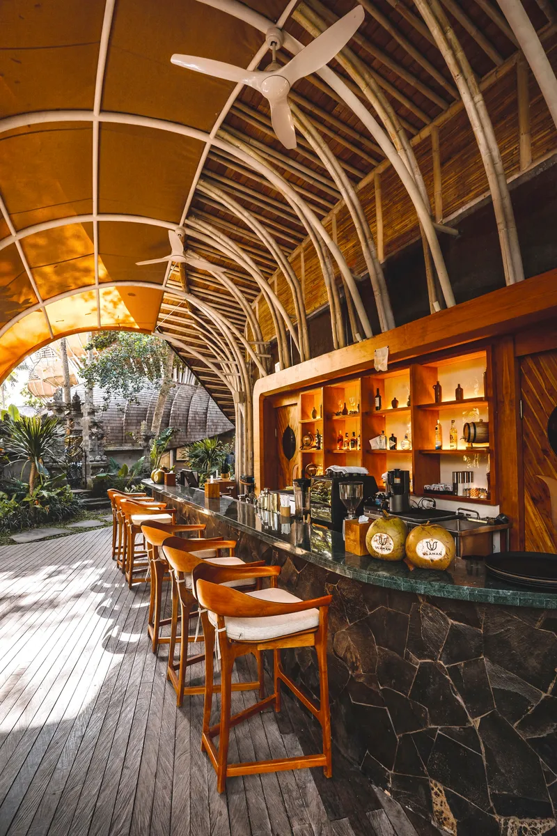Interior bar with dark stone counter under arched bamboo ribs and exposed ceiling fan