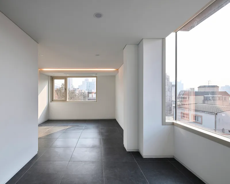 Interior corner with angled window walls and integrated linear lighting above the smaller opening