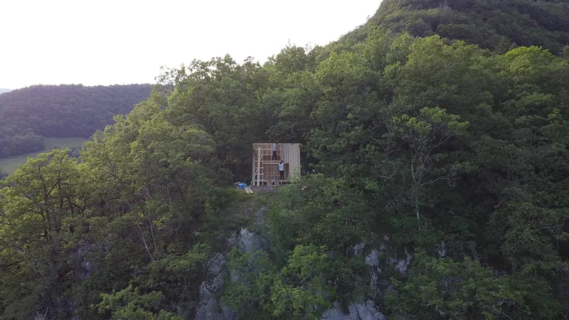 Distant view of the timber structure perched on a forested hillside at twilight