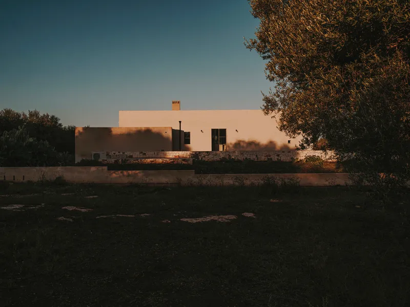Distant view of the white stucco facade framed by olive trees at sunset