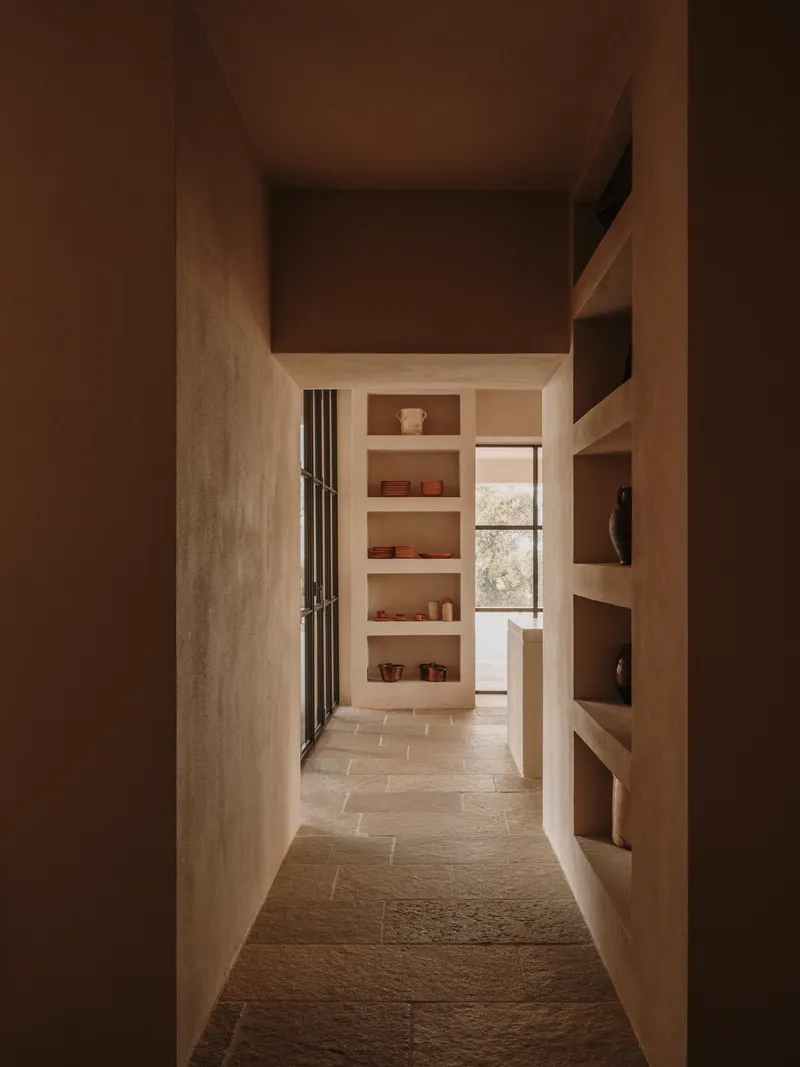 Narrow corridor framed by built-in timber shelving with soft afternoon light filtering through