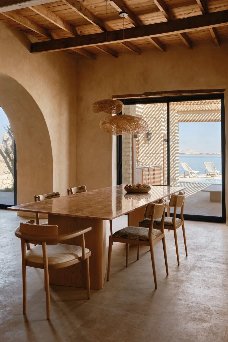 Dining room with exposed timber ceiling beams and woven pendant lights above a wooden table