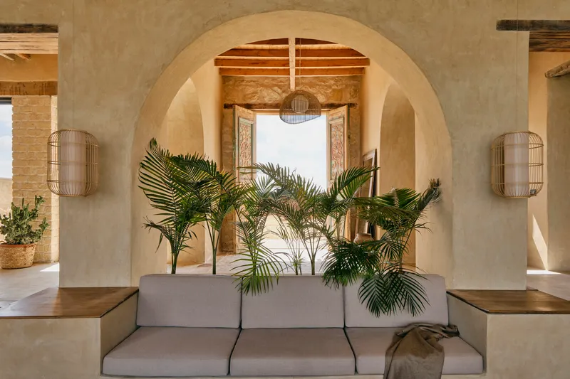 Layered arches framing a seating area with palm plants and woven wall sconces