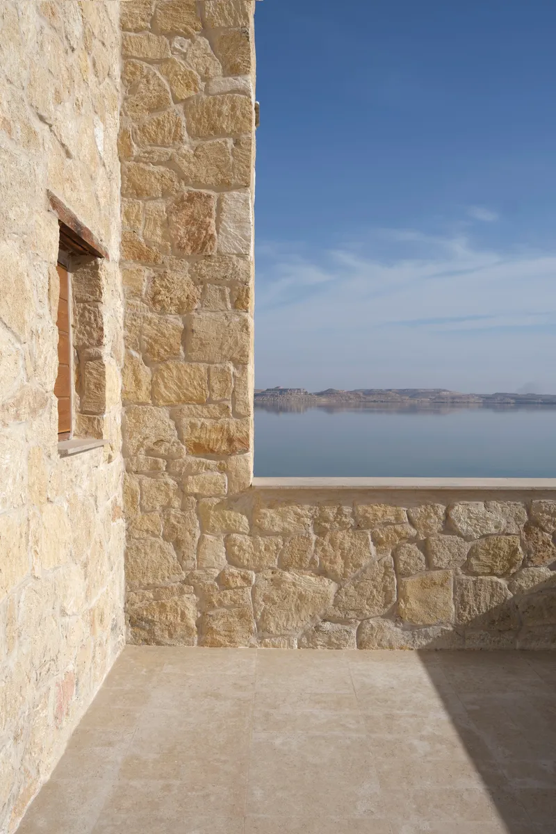 Corner terrace with limestone walls overlooking calm water under clear blue sky