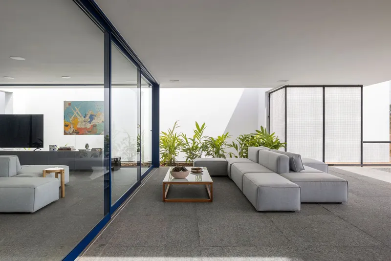 Living room with grey sectional sofa and floor-to-ceiling glazing opening to planted courtyard