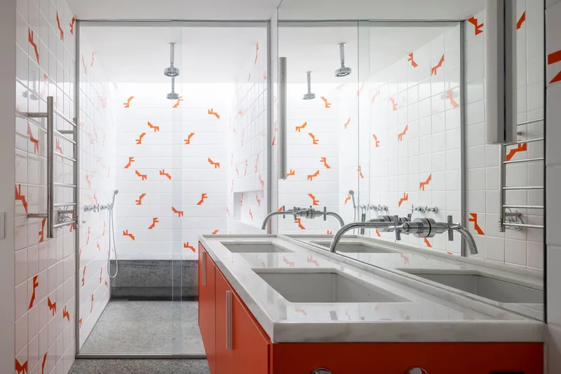 Bathroom vanity with orange cabinetry and white tile walls featuring scattered orange geometric decals