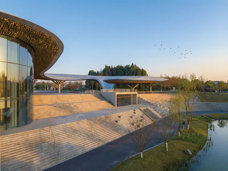 Timber plaza deck extending toward the water's edge at dusk with birds in flight