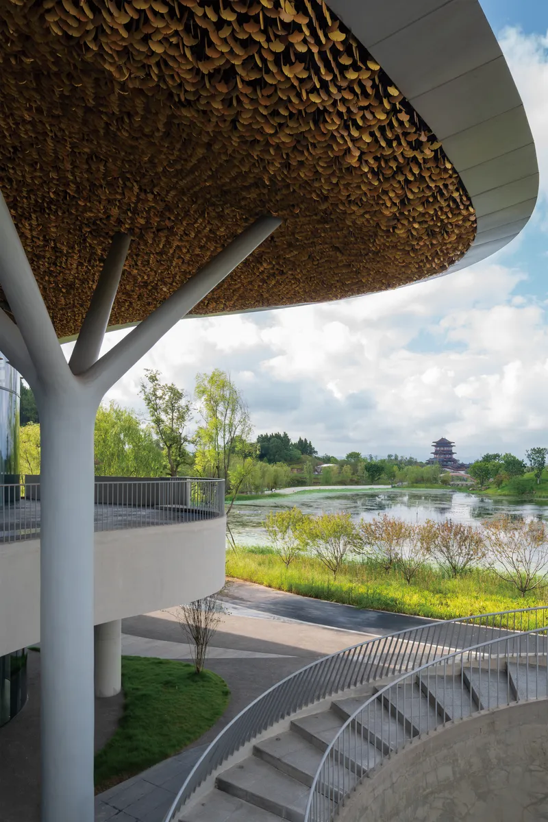 Exterior terrace under the scalloped roof edge overlooking a wetland and distant pagoda