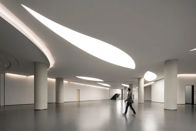 Lobby with curved skylights cutting through the ceiling as a visitor walks across polished floor