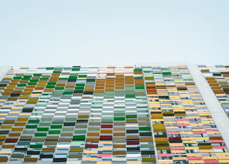 Upward view of the multicoloured ceramic panel facade with green, yellow, and grey rectangular tiles