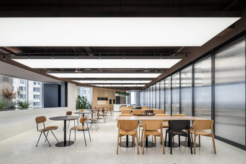 Cafe area with scattered tables and chairs next to floor-to-ceiling translucent glass partitions