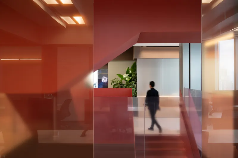 Translucent red glass partitions with a blurred figure walking through the reception area