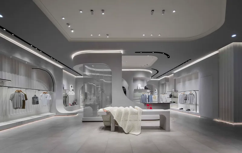 Interior of a retail space with curved white ceiling elements, recessed linear lighting, and central display table
