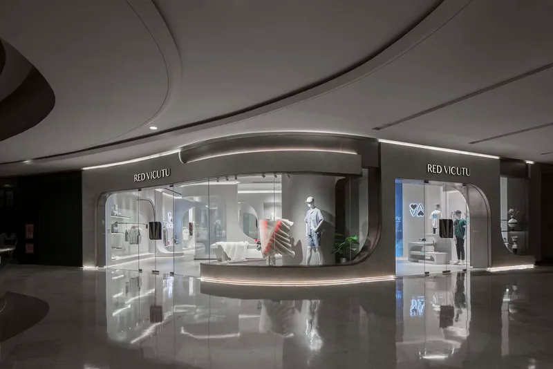 Storefront facade with curved glass and gray stone surround reflected in the glossy mall floor