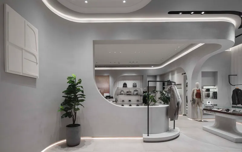 View toward the curved display counter with a potted fiddle-leaf fig beside the white partition wall